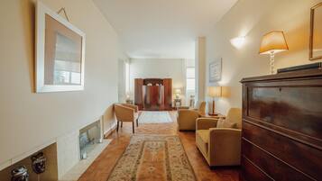 A spacious living room with a fireplace, a wooden cabinet, and a large rug.