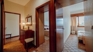 A hotel room with a wooden floor, a desk with a mirror, a chair, a bed, and a window with curtains. - Grand Botanic Garden Apartment by Vacationy (Porto)