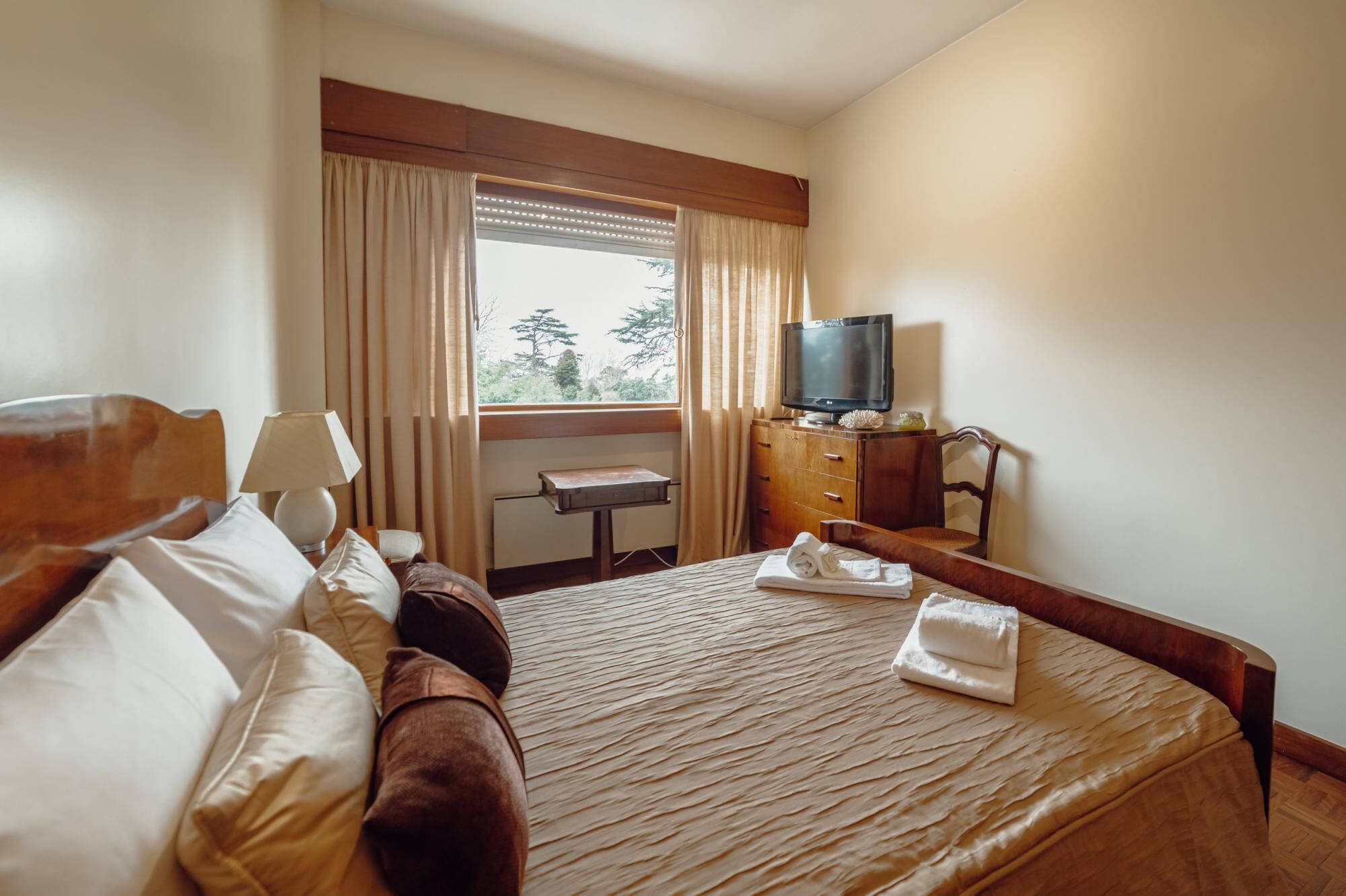 Une chambre d’hôtel avec un lit, un bureau, une télévision et une fenêtre avec des rideaux.