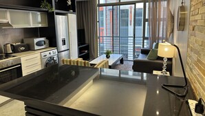 A modern kitchen with a central island, built-in appliances, and a seating area with a view. - Mandela Rhodes W303 (Cape Town)