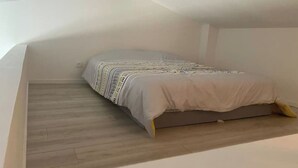A small, single-bed room with a wooden floor and a plain white wall. - T1 in Blaye (Blaye)