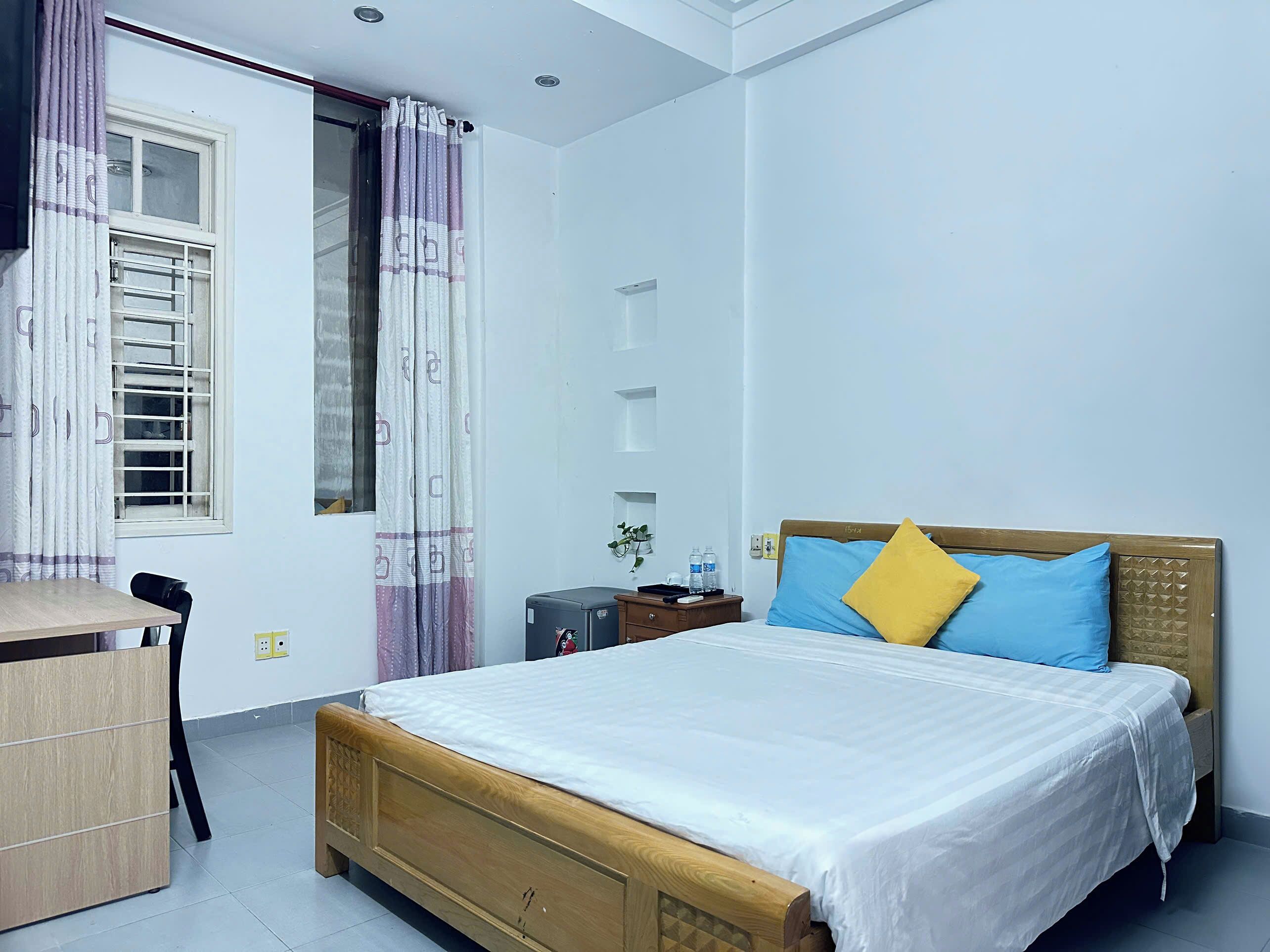 Quarto com cama de madeira, uma escrivaninha e uma cadeira.