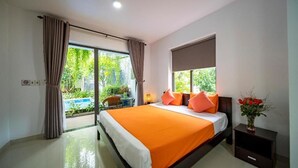 A bedroom with a large bed, a window with curtains, a nightstand, and a view of greenery outside. - My Anh Boutique Villa Hoi An (Da Nang)