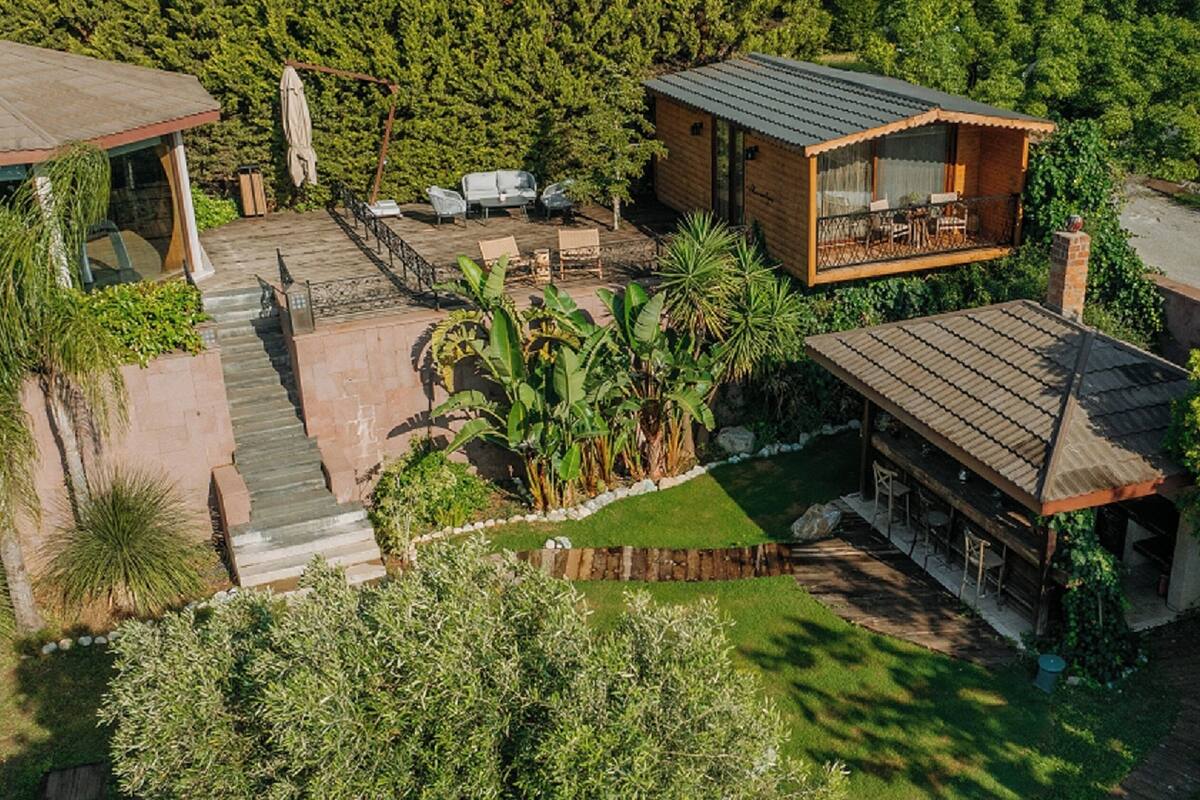A modern house with a covered patio, a small outdoor seating area, and a staircase leading to a deck.