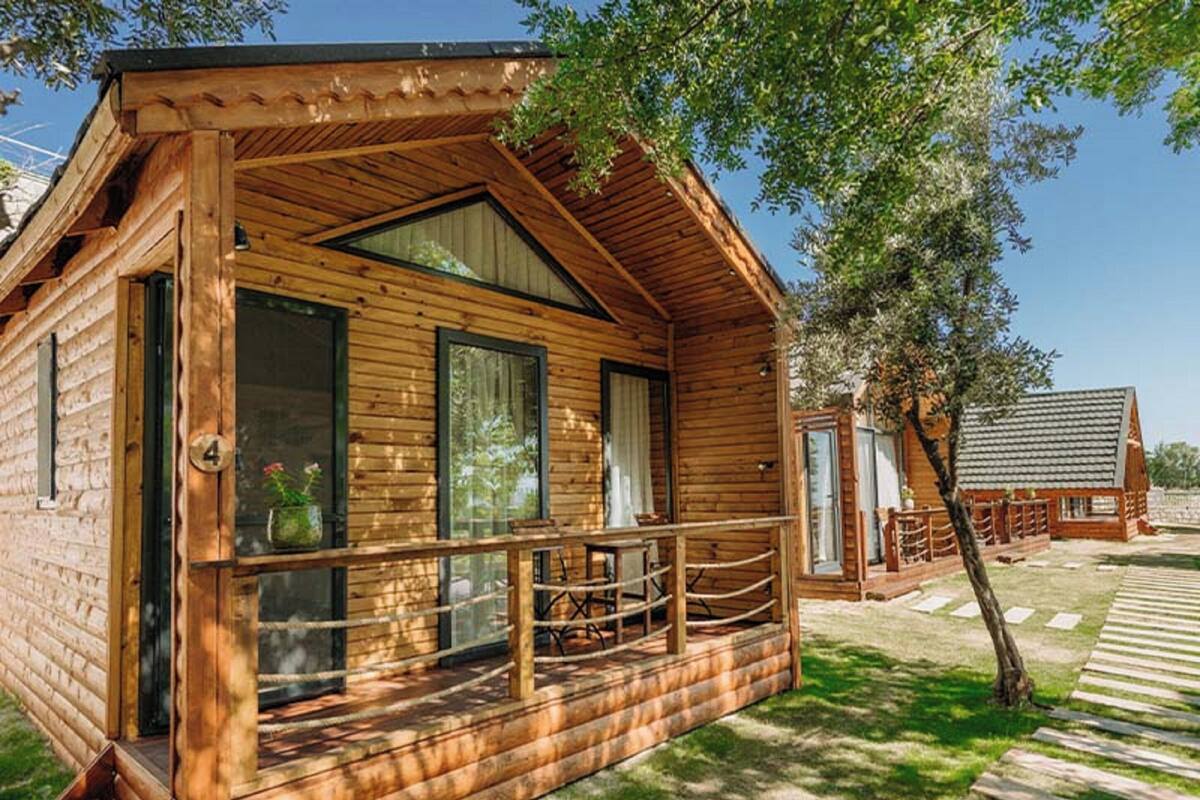 A wooden cabin with a porch, large windows, and a small deck.