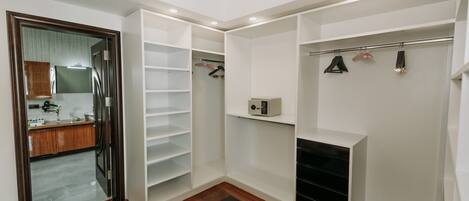 A walk-in closet with open shelving, a coat rack, and a small heater.