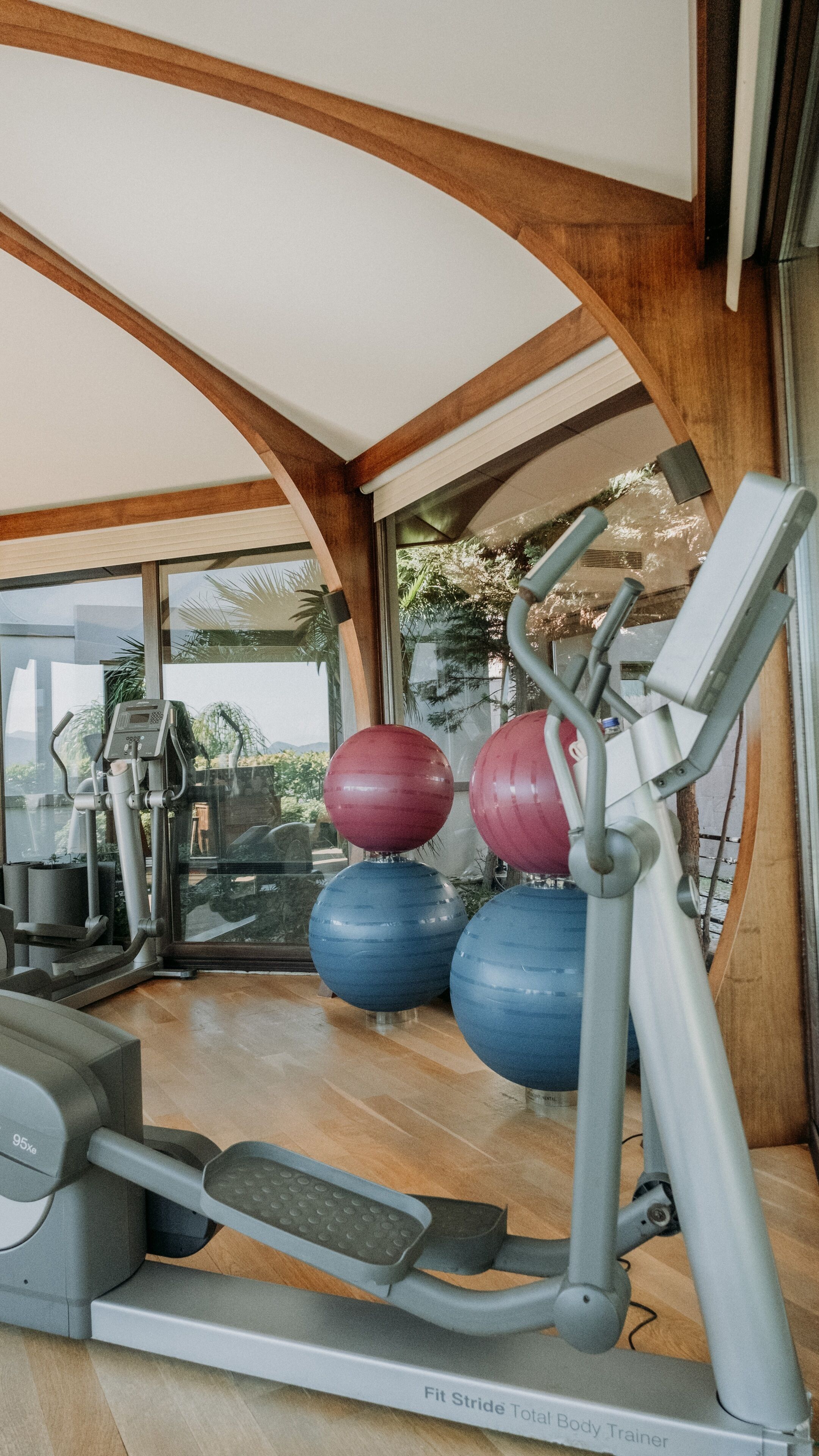 A gym with a treadmill, elliptical, and exercise balls.