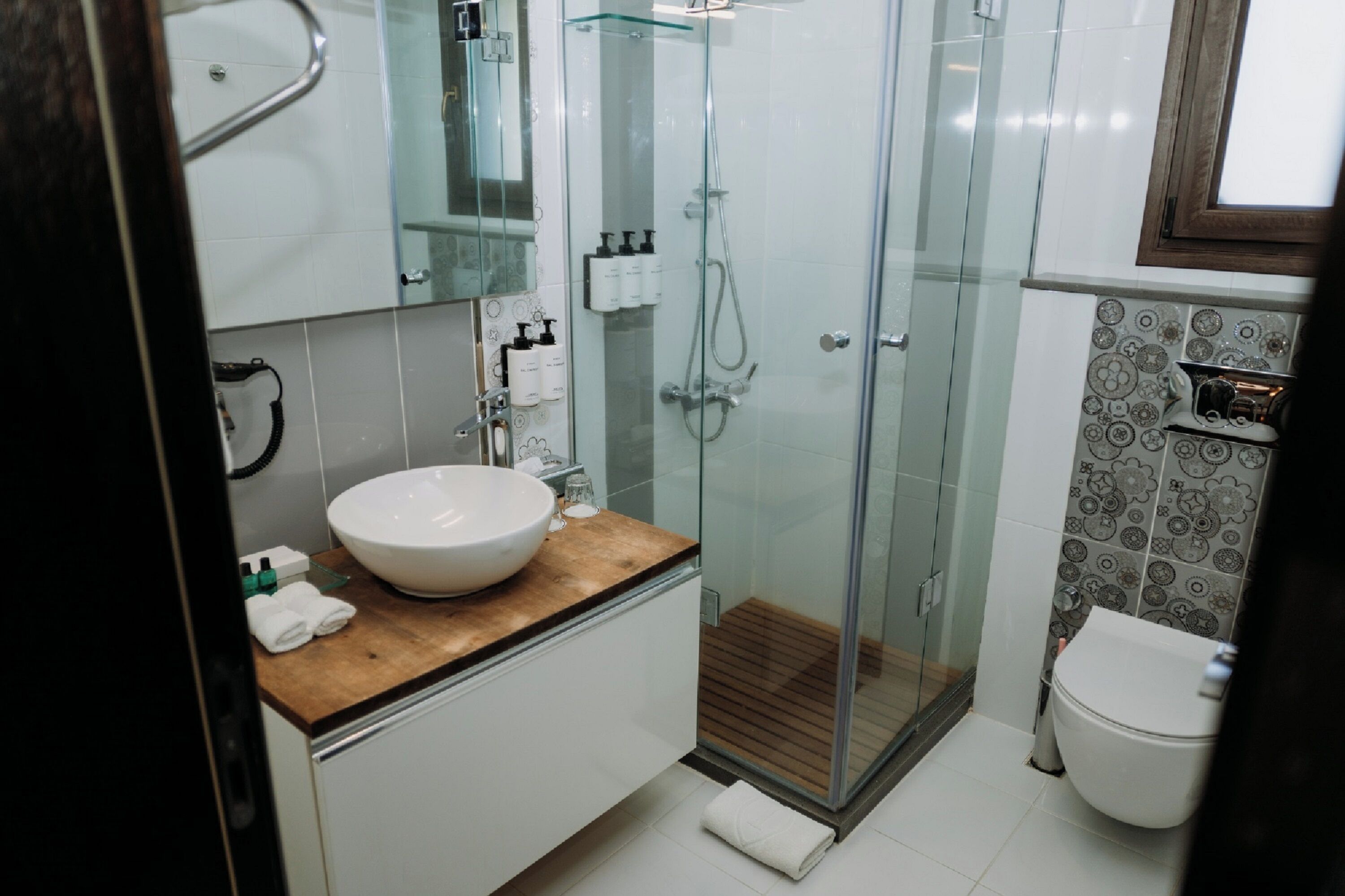 A modern bathroom with a glass-enclosed shower, a large white sink, and a toilet.