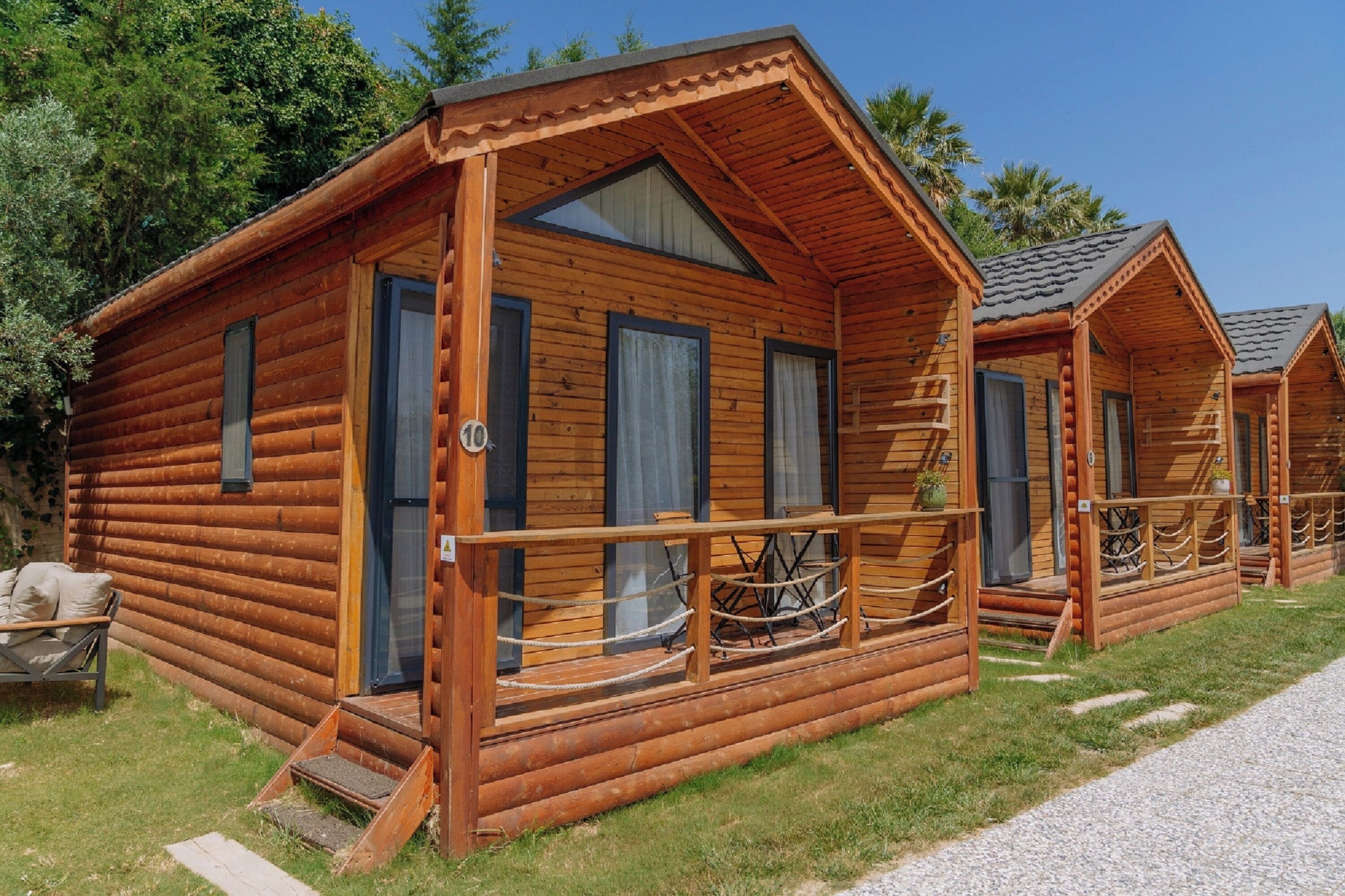 A row of wooden cabins with a porch, a door, and a window.