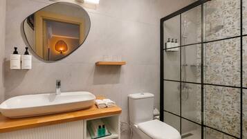 Un baño moderno con un lavamanos ovalado grande, un inodoro y una ducha con cerramiento de vidrio.