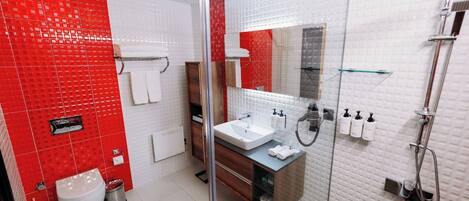 A modern bathroom with a red and white tiled wall, a glass shower enclosure, a sink with a mirror, and a toilet.
