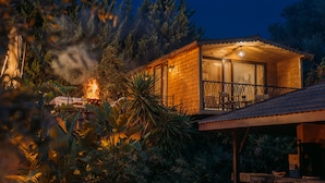 A wooden cabin with a balcony, surrounded by dense foliage and trees. - Doors Urla Hotel & Bungalows (Urla)