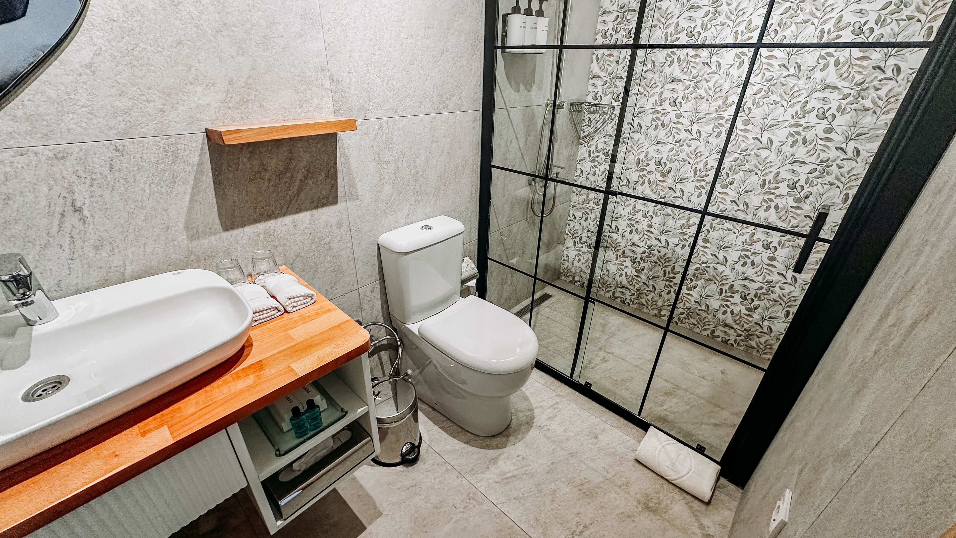 Un baño con tocador de madera, lavamanos blanco y retrete.