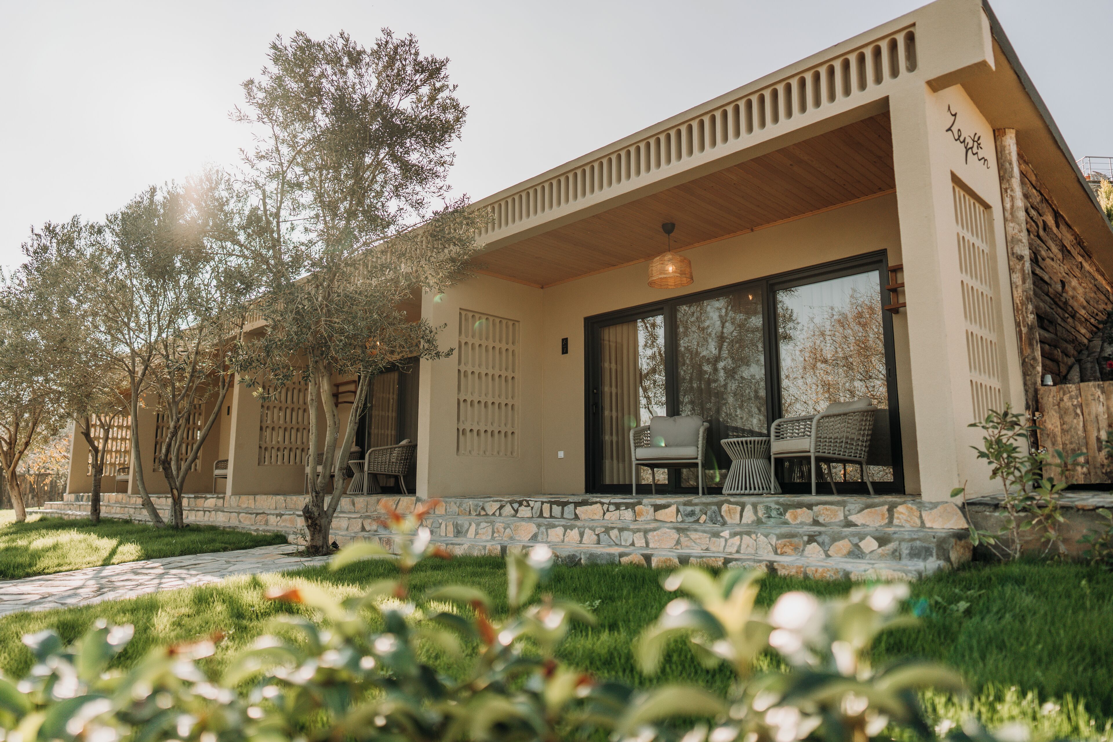 A modern house with a stone facade, large glass windows, and a wooden porch.