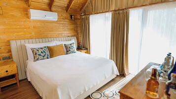 A wooden room with a bed, nightstands, and a window with curtains.