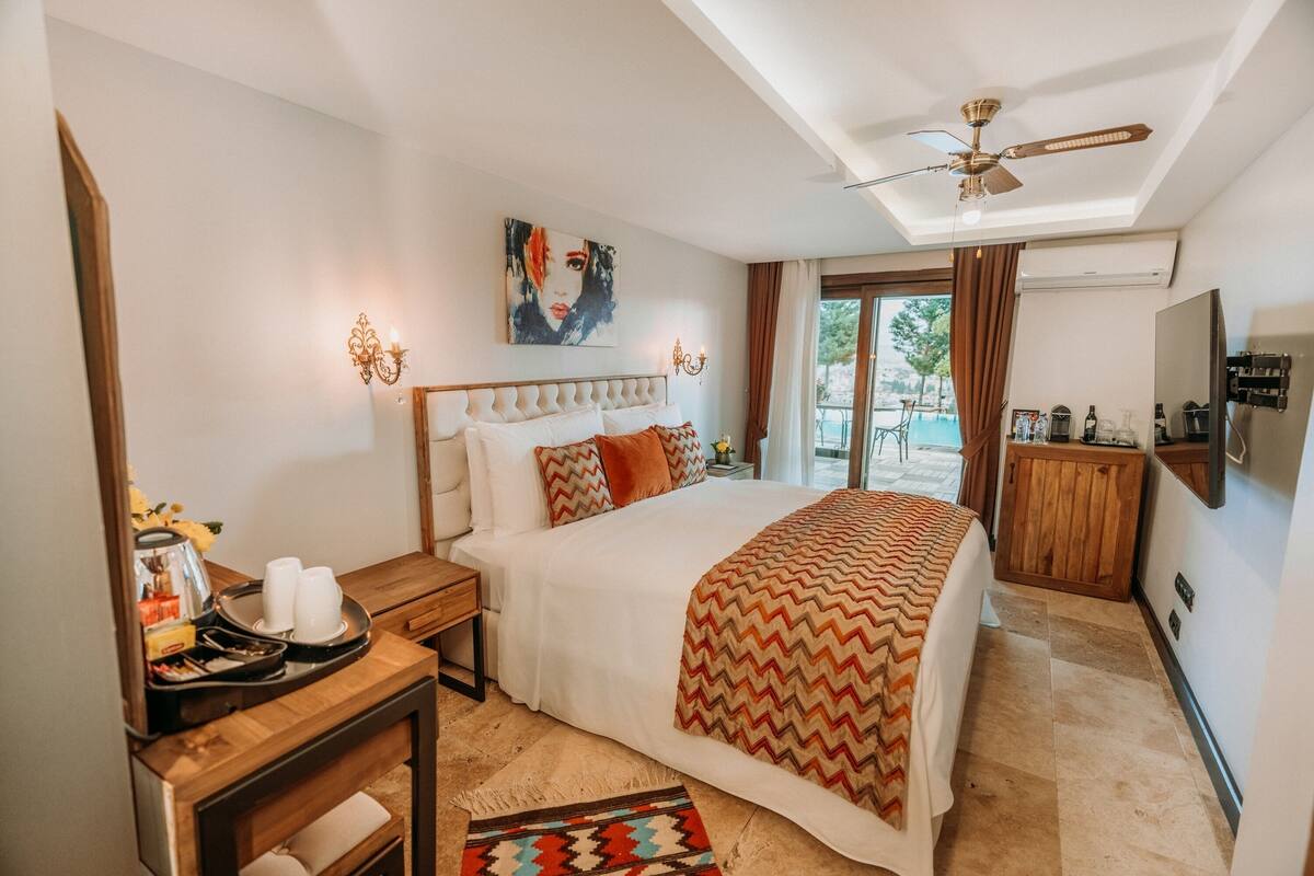 A bedroom with a bed, bedside table, and a view of the outdoors.