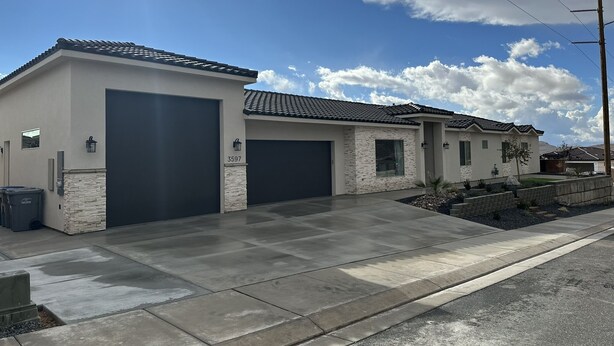 A modern two-story house with a stone facade, two garage doors, and a well-maintained driveway. - Zions Gate Casita (Hurricane)