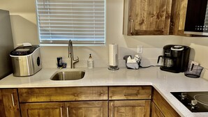 A kitchen with a stainless steel sink, a Keurig coffee maker, a paper towel dispenser, and wooden cabinets. - Zions Gate Casita (Hurricane)