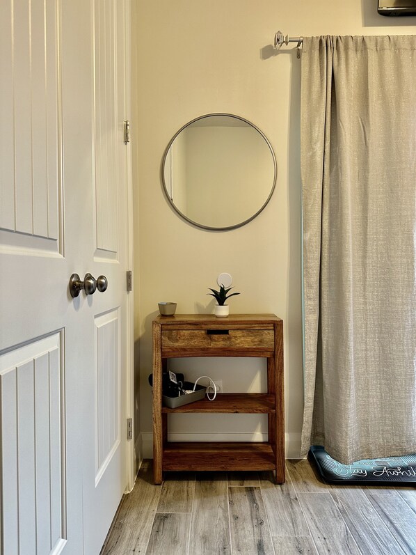 Une salle de bain avec un meuble-lavabo en bois, un miroir rond, une petite plante et un rideau de douche.
