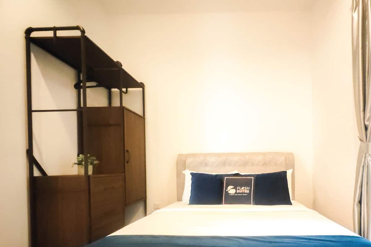 A bedroom with a bed, a wooden wardrobe, a window with curtains, and a sign on the bed.