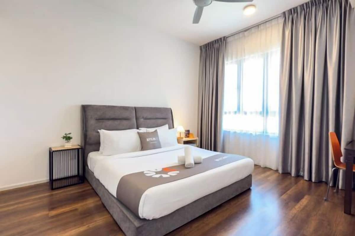 A hotel room with a bed, a nightstand, a chair, and a window with curtains.
