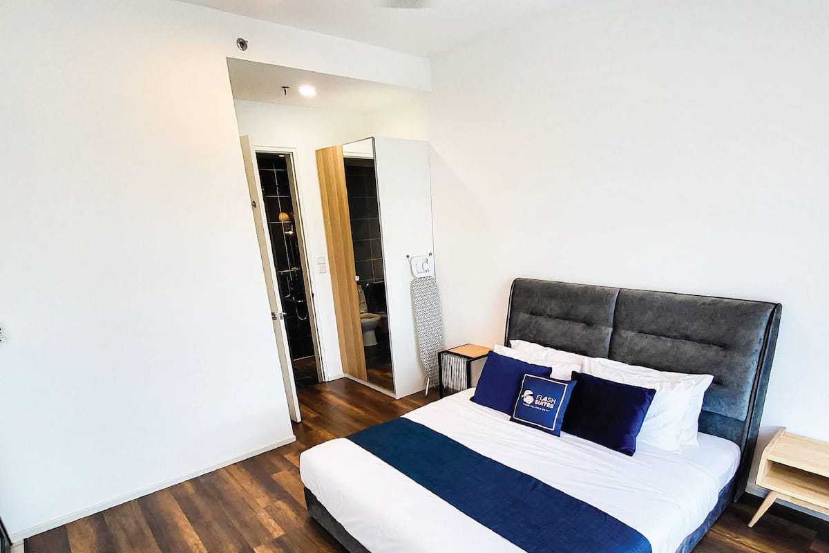 A modern hotel room with a large bed, a small bedside table, and a built-in wardrobe.