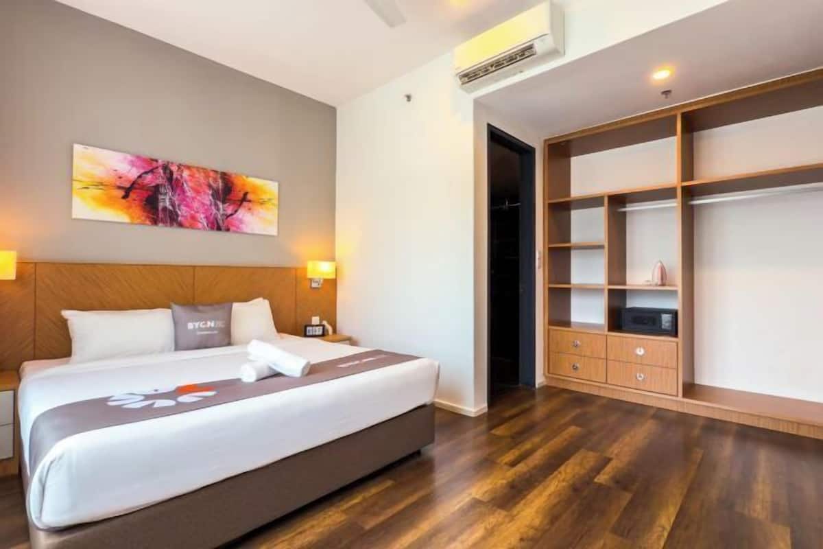 A hotel room with a bed, a nightstand, a wall-mounted air conditioner, and a built-in wardrobe.