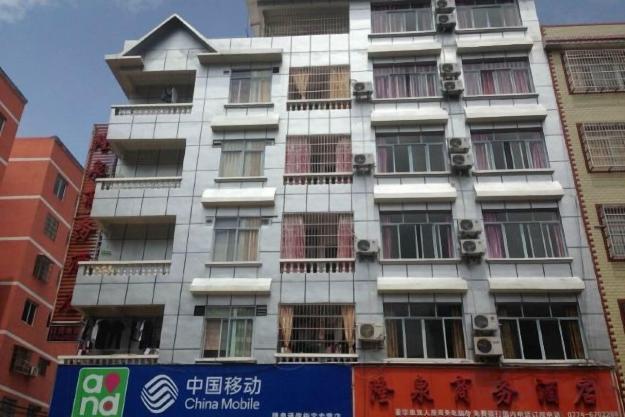 Un edificio de varios pisos con balcones, unidades de aire acondicionado y un letrero de China Mobile.
