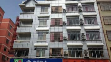 Un edificio de varios pisos con balcones, unidades de aire acondicionado y un letrero de China Mobile.