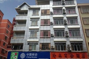A multi-story building with balconies, air conditioning units, and a sign for China Mobile. - Hezhou Huangyao Longquan Business Hotel (Zhaoping)