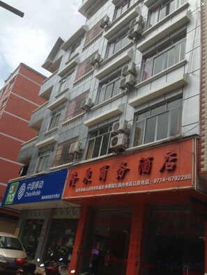 A multi-story building with a red storefront and a blue sign for China Mobile. - Hezhou Huangyao Longquan Business Hotel (Zhaoping)