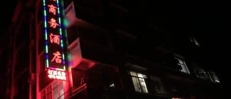 Un bâtiment doté d’une enseigne lumineuse, d’une entrée bien visible et d’une fenêtre laissant voir de la lumière à l’intérieur.