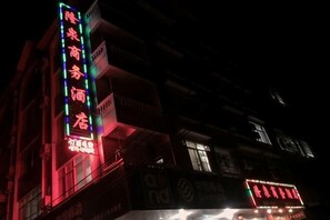 Um edifício com letreiros iluminados, entrada visível e varanda.