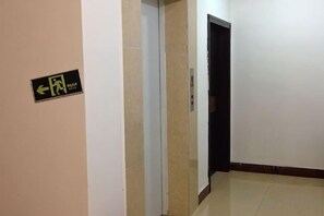 A corridor with a sign indicating an exit and an elevator. - Hezhou Huangyao Longquan Business Hotel (Zhaoping)
