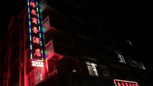 A building with illuminated signage, including a prominent vertical sign with text and a horizontal sign with numbers. - Hezhou Huangyao Longquan Business Hotel (Zhaoping)
