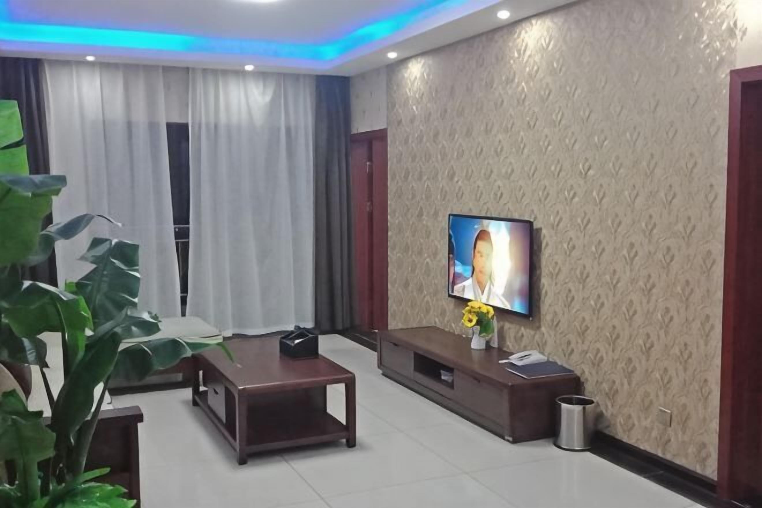 Una sala moderna con una televisión de pantalla plana, un sofá, una mesa de centro y una planta.