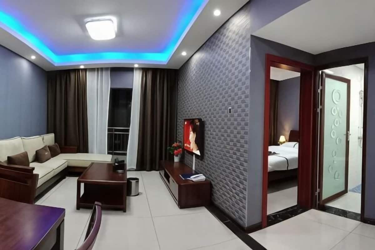 Een moderne hotelkamer met een bank, televisie en een balkon.