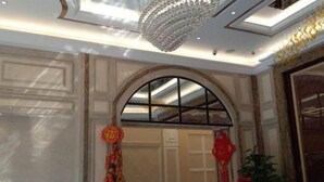 A room with a chandelier, a large arched window, and traditional decorations. - Yashige Apartment Ruili (Ruili)