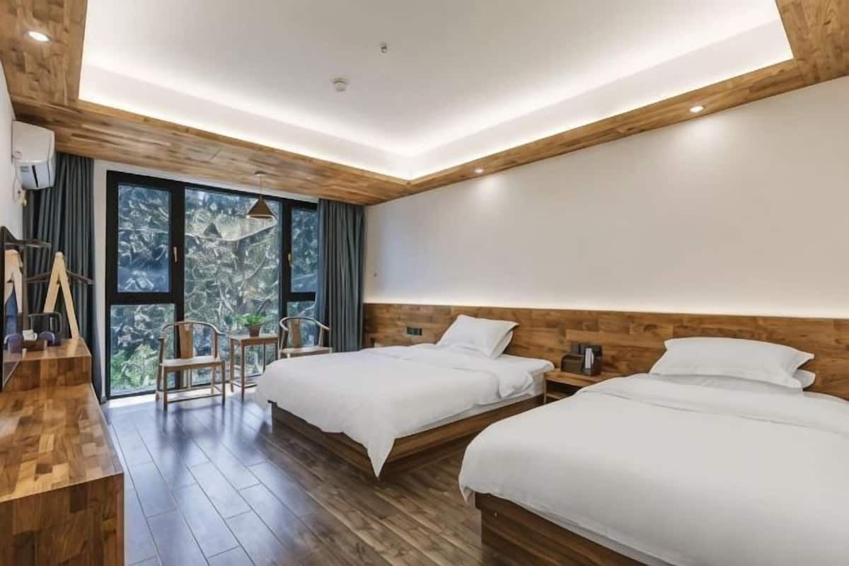 Una habitación de hotel moderna con dos camas, techo de madera y un ventanal grande.