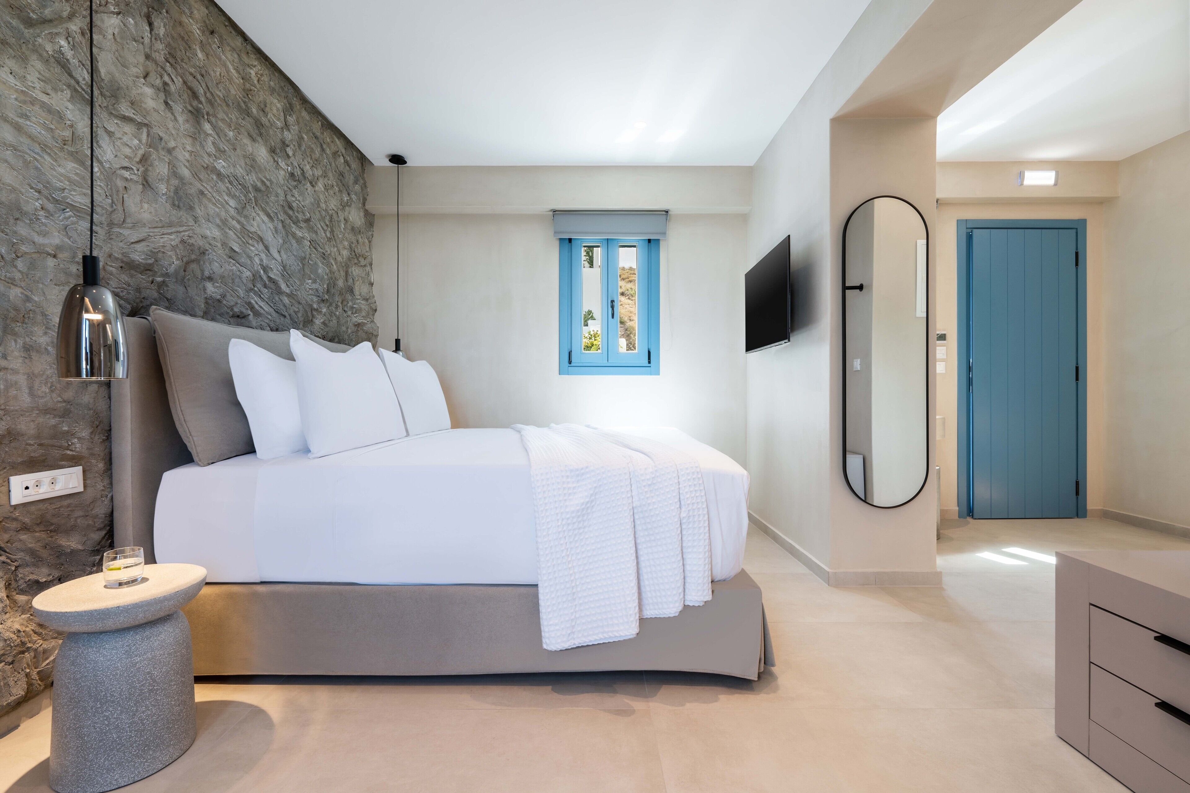 Un dormitorio moderno con cama, mesita de noche y un espejo grande.