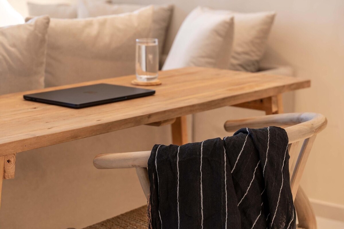 Una mesa de madera con una computadora portátil y un vaso de agua.