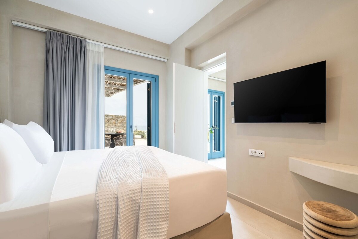 Habitación de hotel con cama, televisor montado en la pared y vistas al exterior.