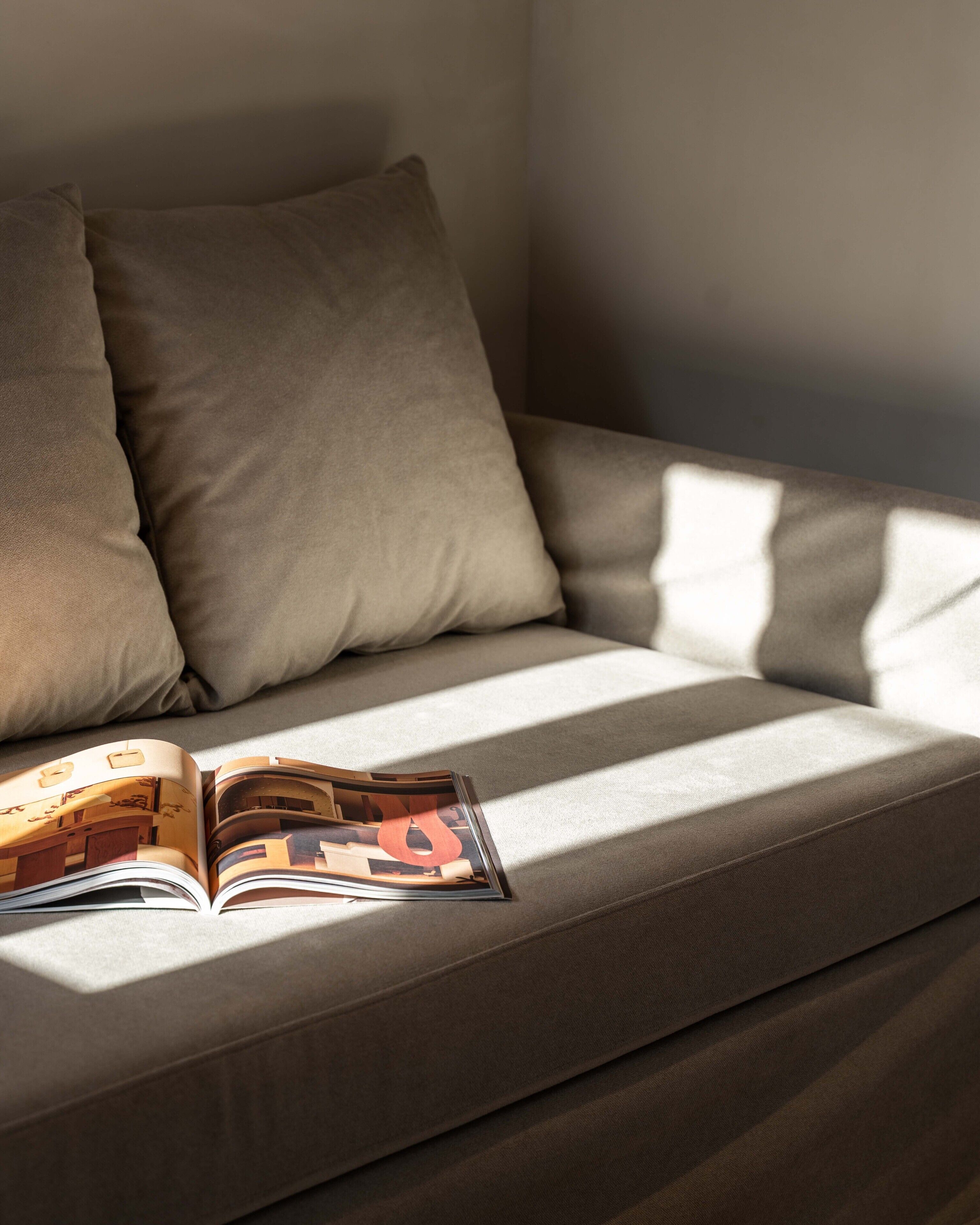Ein Sofa mit Kissen und einer Zeitschrift darauf.