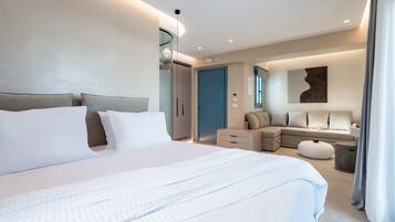 A modern hotel room with a large bed, a sofa, a small table, and a mirror.