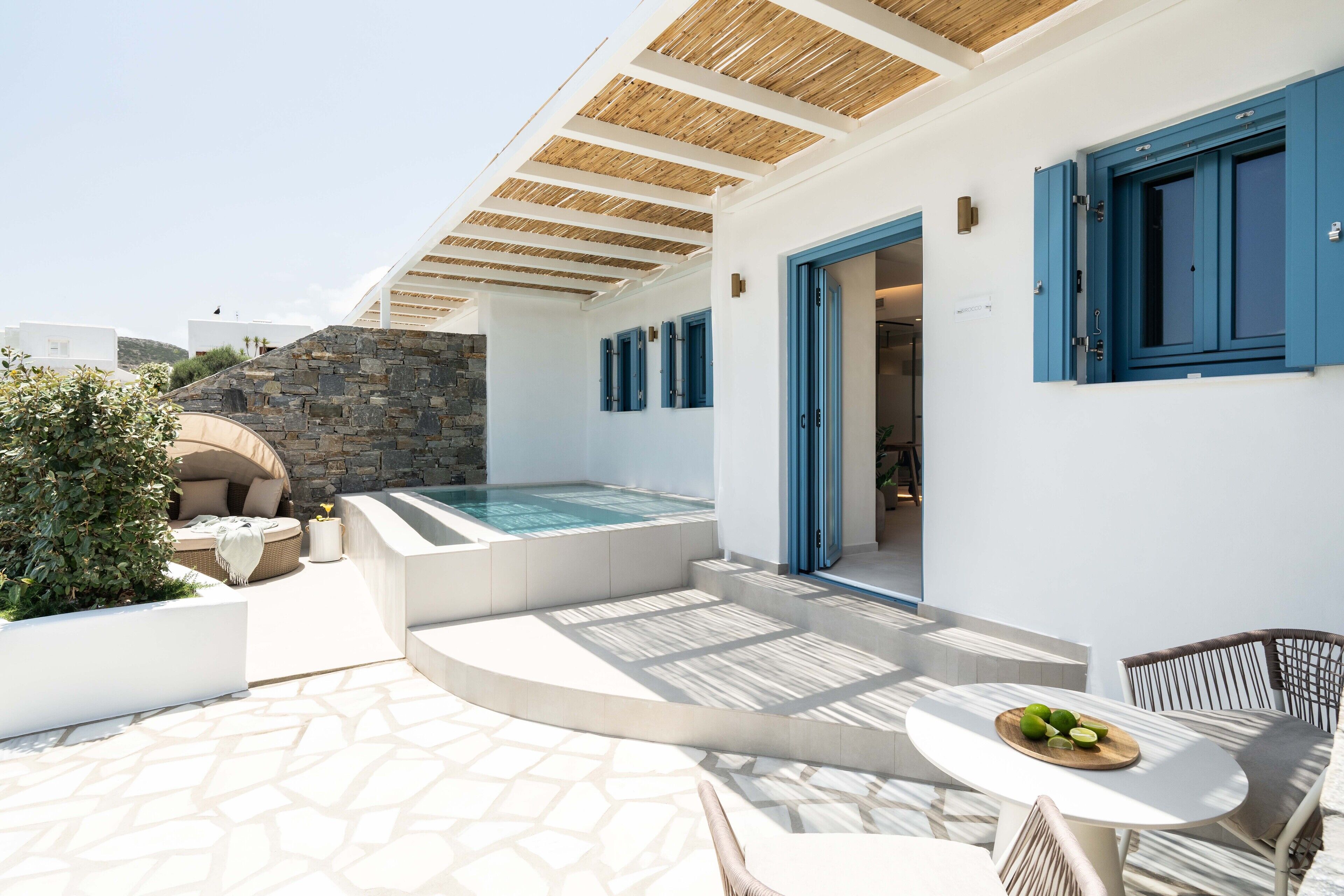 A modern outdoor area with a stone wall, a hot tub, and a seating area with a table and chairs.