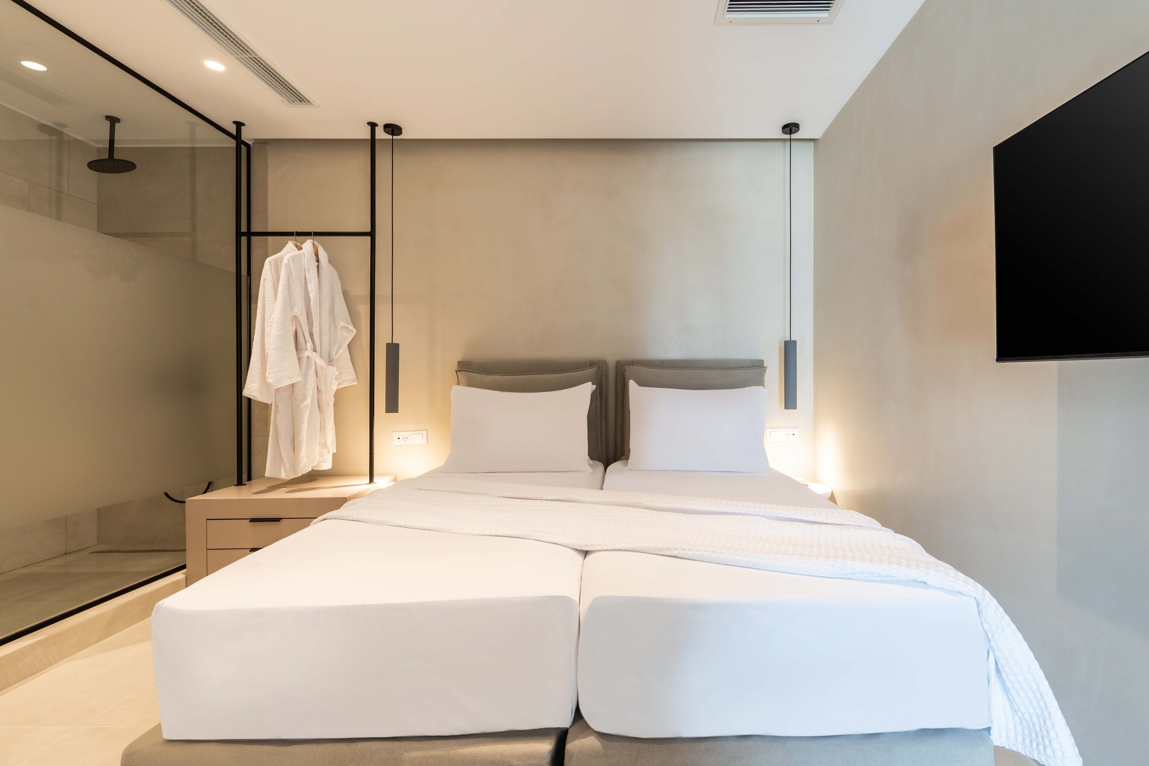 Une chambre d’hôtel moderne dotée d’un grand lit, d’une douche à parois de verre et d’un téléviseur fixé au mur.