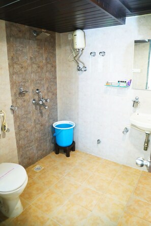 Une salle de bain avec des toilettes, un lavabo, une douche et un seau bleu.