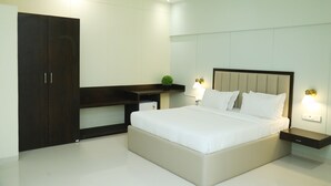 A modern bedroom with a large bed, bedside tables, a dark wooden wardrobe, and a small plant on a shelf. - Turtle Hotel (Mumbai)