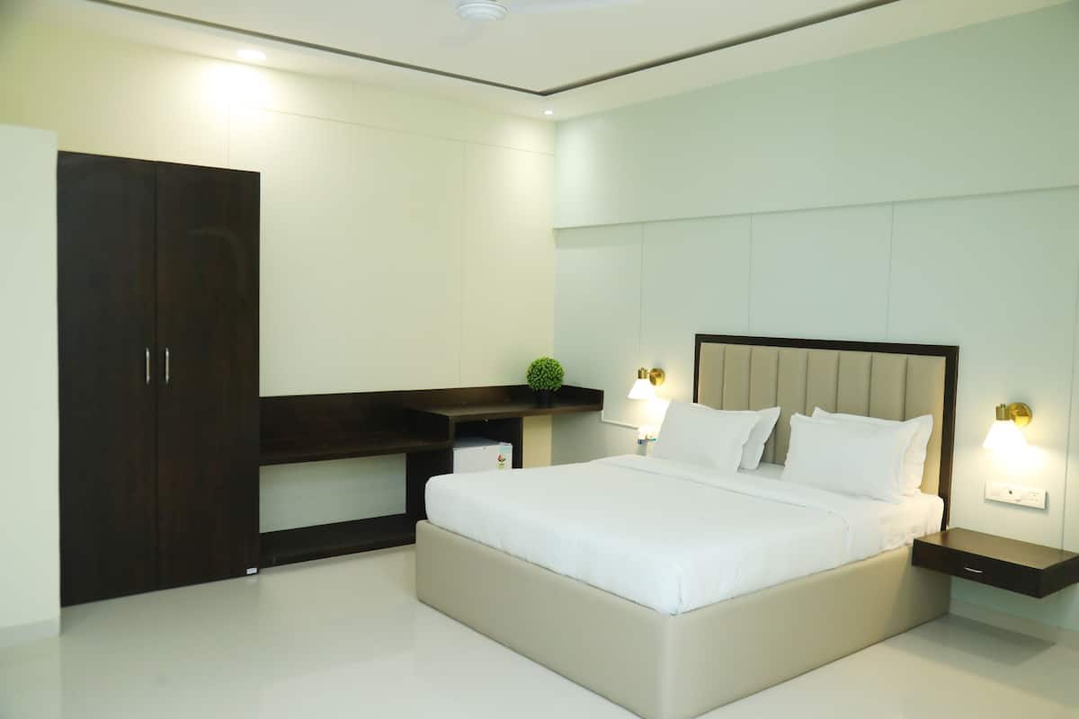 A modern bedroom with a large bed, bedside tables, a dark wooden wardrobe, and a small plant on a shelf.