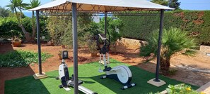Work out in a serene garden setting with a stationary bike and rowing machine.